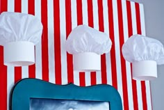 a photo frame with paper hats hanging from it's sides on a striped wall