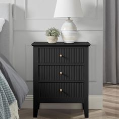 a night stand with two drawers and a white vase on the nightstand next to it