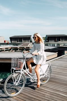 a woman riding a bike down a wooden pier