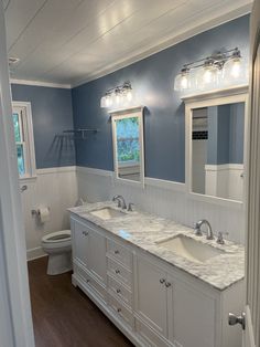 a bathroom with double sinks and two mirrors on the wall, along with blue walls