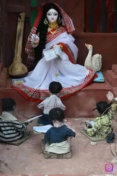 a statue of a woman sitting on top of a stage surrounded by small children in front of her