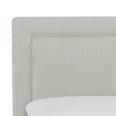 an upholstered headboard with pinstripe pattern and white sheets on it