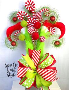 a green and red bow with candy canes on it's side, sitting on top of a table