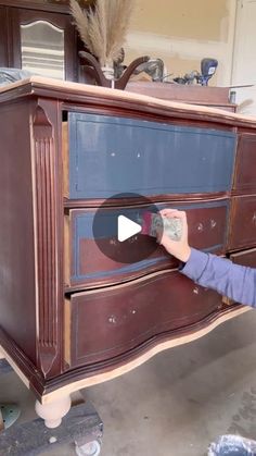 a woman is painting an old dresser with blue and brown paint on the top shelf