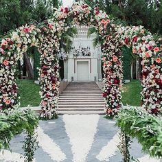 an outdoor wedding ceremony with flowers and greenery on the steps to the front door