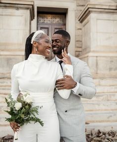 a man and woman standing next to each other in front of a building