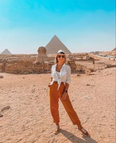 a woman standing in front of the pyramids at giza, with her hands on her hips