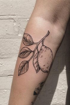 a black and white tattoo on the arm of a woman with an orange tree branch