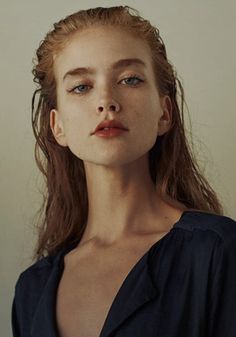 a woman with long red hair and blue eyes wearing a black shirt looking at the camera