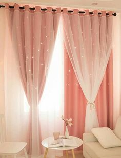 a living room with pink curtains and white furniture