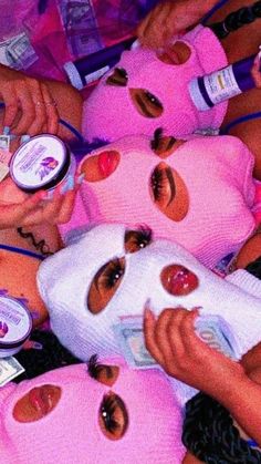 several girls with pink masks on their faces and one girl has her eyes closed while the others are holding lip bales