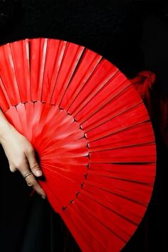 a woman holding a red fan in her hand