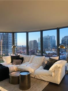 a living room filled with lots of furniture and large windows overlooking the cityscape