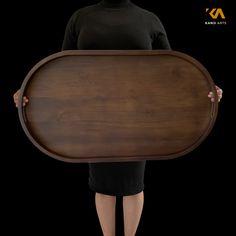 a woman holding a large wooden tray in her hands