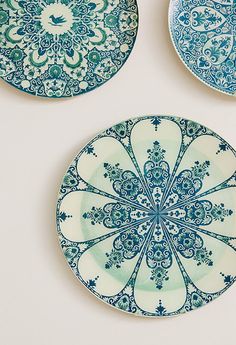 three plates with blue designs on them are hanging on the wall next to each other