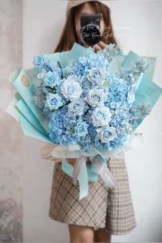 a woman holding a bouquet of blue flowers