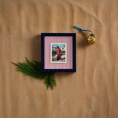 a christmas ornament with a photo on it and a pine branch next to it