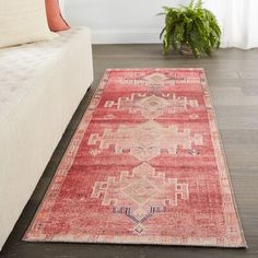 a large red rug in the middle of a living room with a couch and potted plant