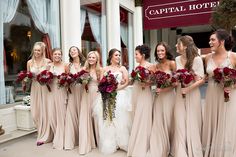 a group of women standing next to each other in front of a building holding bouquets