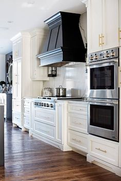 a large kitchen with white cabinets and stainless steel appliances, along with hardwood flooring