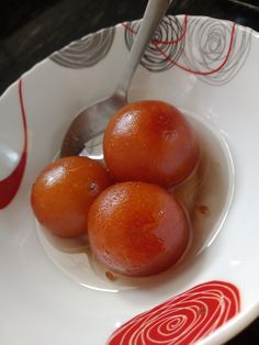 three oranges in a white bowl with a spoon