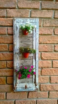 an old window is decorated with potted plants and hanging on the brick wall behind it