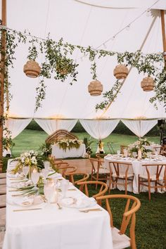 an outdoor tent with tables and chairs set up for a wedding reception in the grass