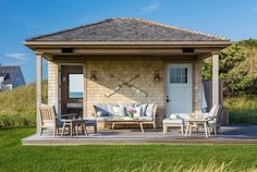 an outdoor living area with chairs, table and couches in front of the house