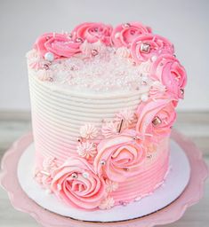 a white and pink cake with flowers on top is sitting on a pink platter