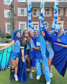 group of girls in blue costumes posing for the camera with a butterfly on their shoulder