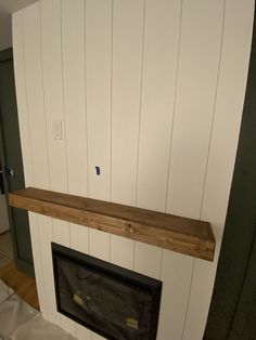 a fireplace with white painted walls and a wooden mantle