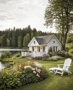 a white house sitting on top of a lush green field next to a lake filled with flowers