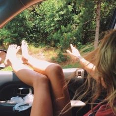 two people sitting in the back seat of a car with their feet up on the dashboard