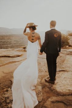 a bride and groom walking on top of a mountain