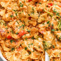 a pan filled with pasta and chicken covered in sauce, garnished with parsley