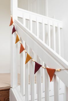 a string of pennants is hanging on the bannister rail in this white room