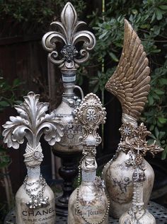 three silver vases sitting on top of a table next to each other with wings