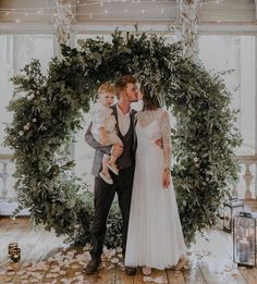 a bride and groom kissing in front of a wreath