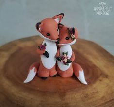 two small figurines sitting on top of a wooden table next to each other