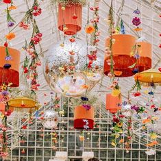 a room filled with lots of different colored lights and hanging flowers on the ceiling above it