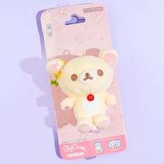 a small white teddy bear with a flower in its mouth on a pink package packaging