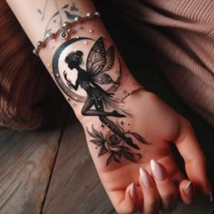 a woman's hand with a tattoo on it and a fairy sitting on the moon