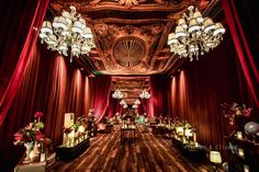 an elaborately decorated hall with chandeliers and red drapes