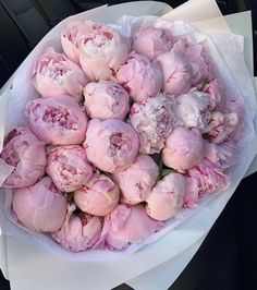 a bouquet of pink peonies sitting on top of a white paper wrapper