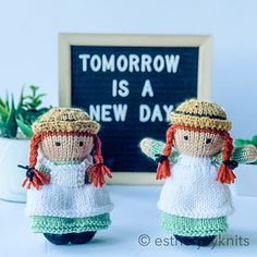 two knitted dolls are standing next to a chalkboard with tomorrow is a new day written on it