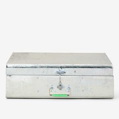 an old metal box sitting on top of a white floor next to a green light