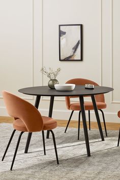 a dining table with four chairs and a bowl on top of it in front of a white wall