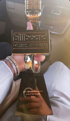 a person holding up an award in their hand while sitting in a car with the sun shining on them