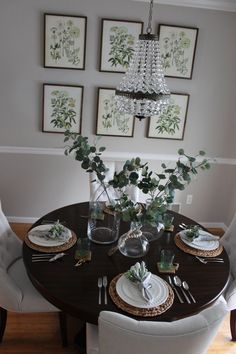 a dining room table with plates and place settings on it, surrounded by framed pictures