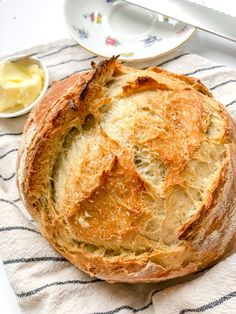 a loaf of bread sitting on top of a towel next to a bowl of butter